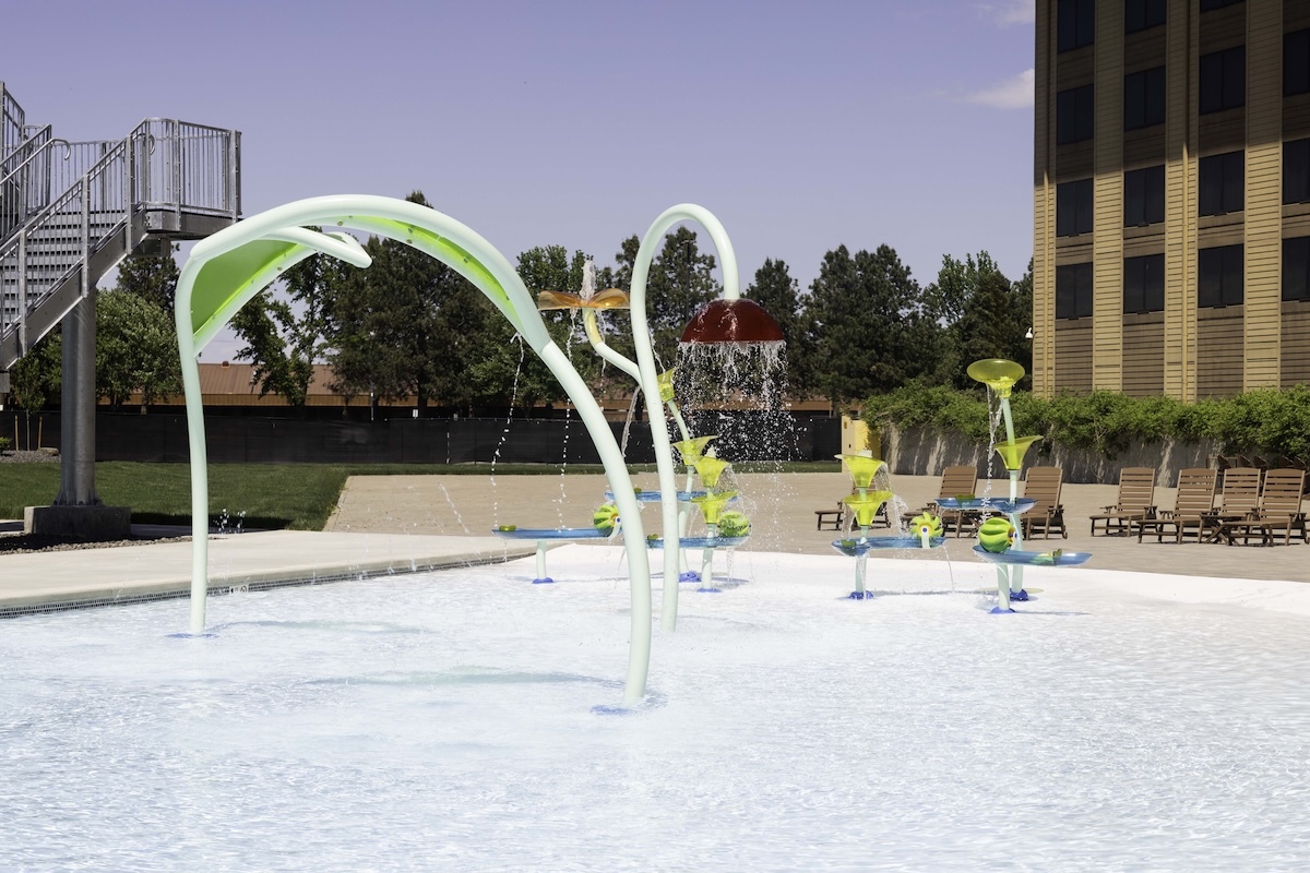 Legends Casino Hotel signature splash pad with beach-style entry and noodle-like sprayers that cascade cooling waters all around pool-goers.
