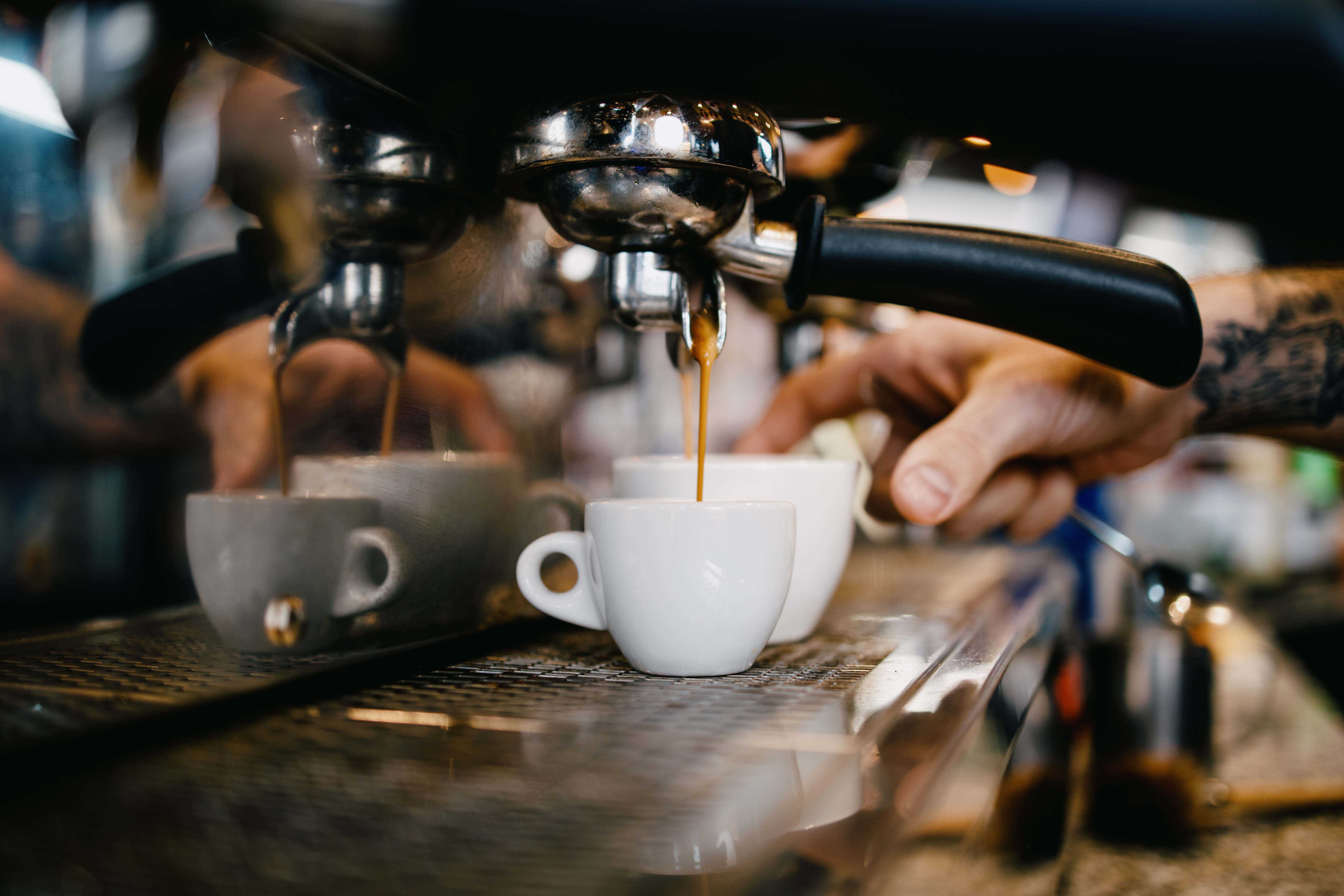 Café expreso que sale de la máquina y cae en una pequeña taza blanca de café