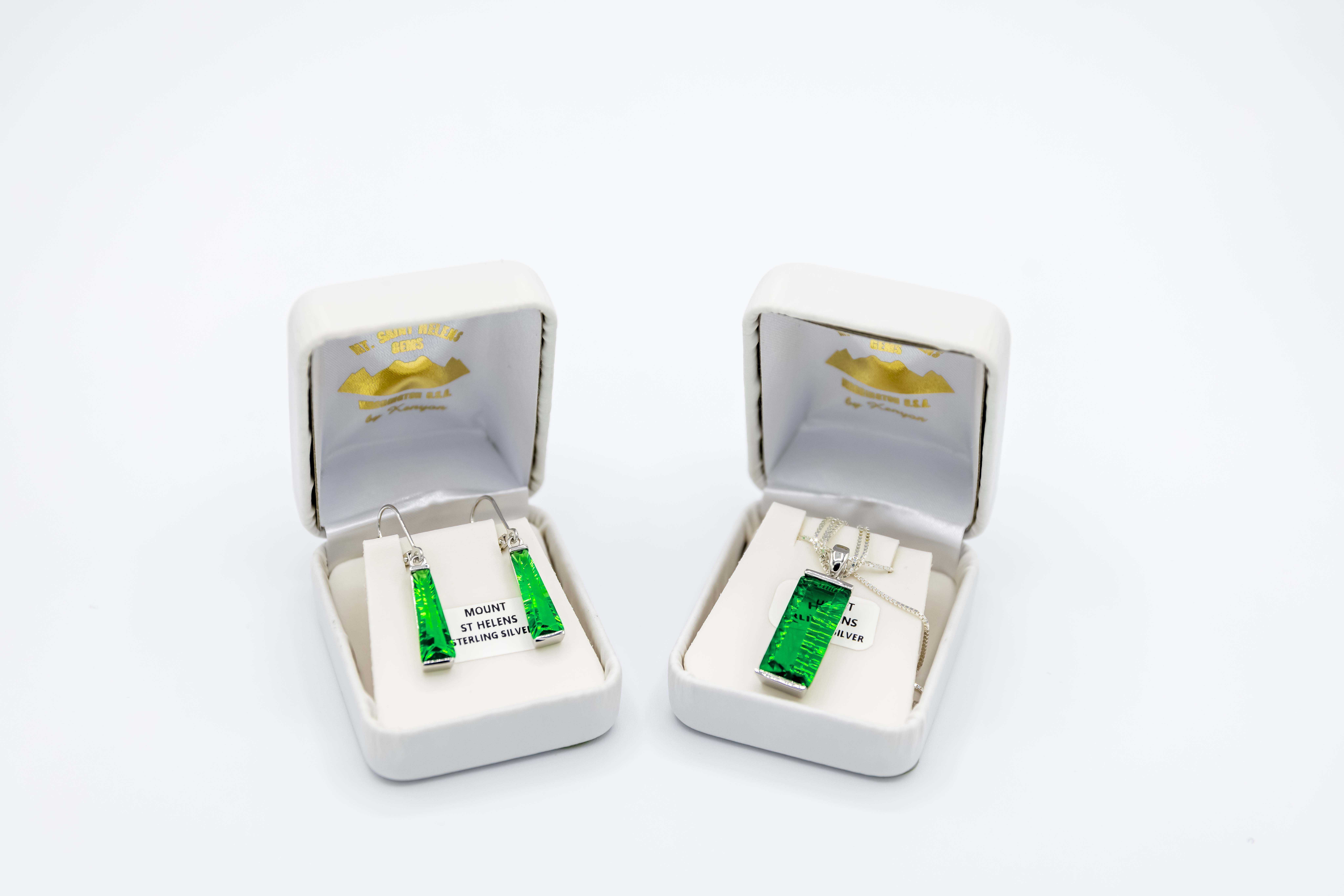 Un par de pendientes de jade y un collar de jade en cajas blancas clásicas de la tienda de regalos Legends